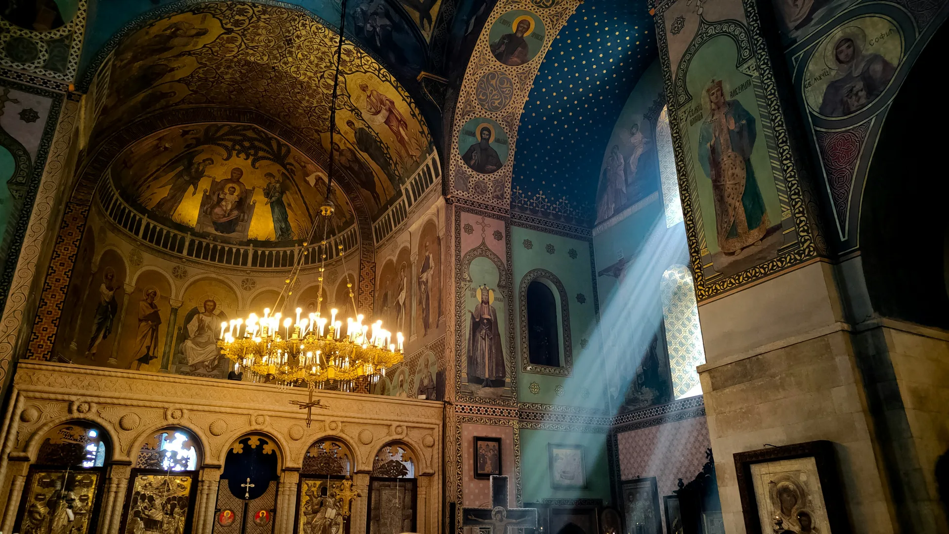 Interior of an Orthodox cathedral with golden dome, icons, and candlelight