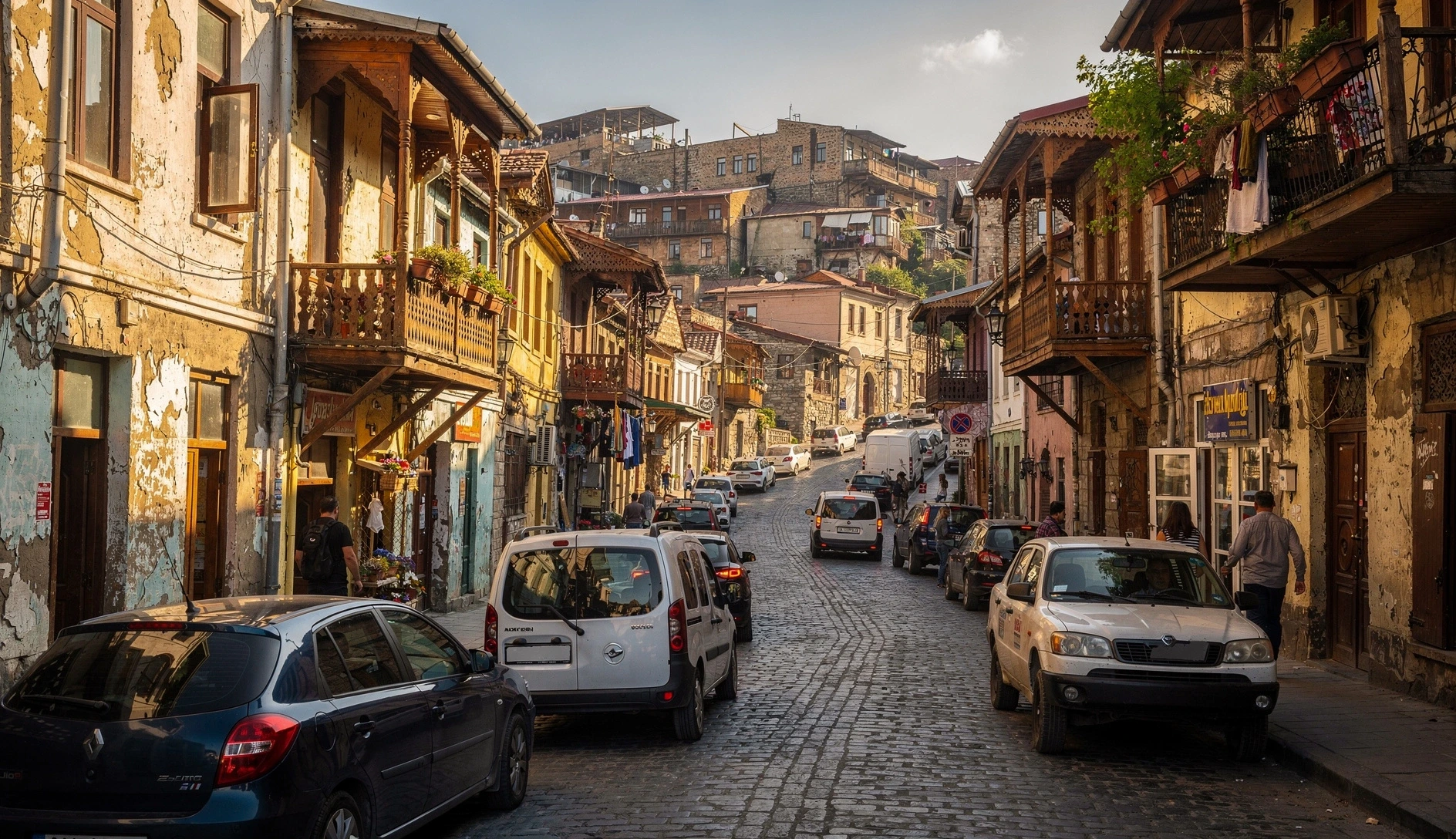 Narrow Old Town street in Tbilisi with cars navigating between buildings with traditional wooden balconies