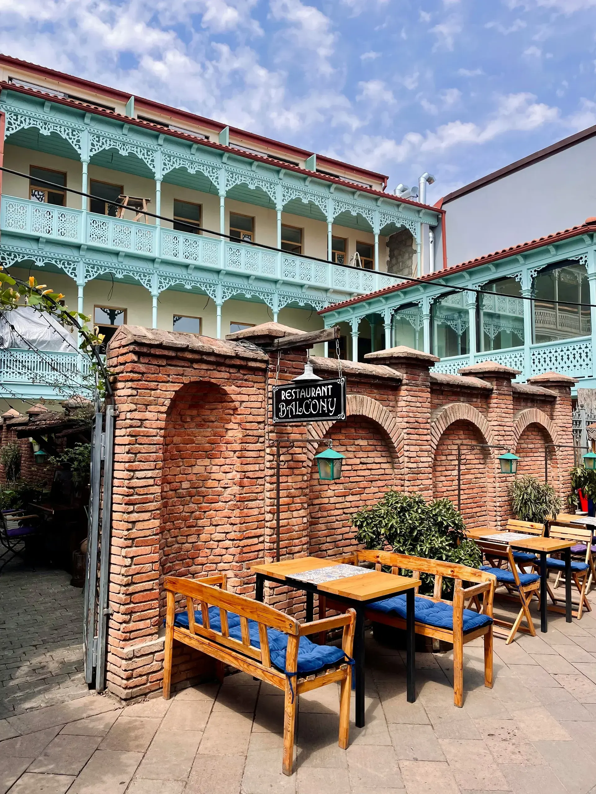 Outdoor restaurant terrace in Tbilisi's Old Town with traditional wooden balconies and brick arches