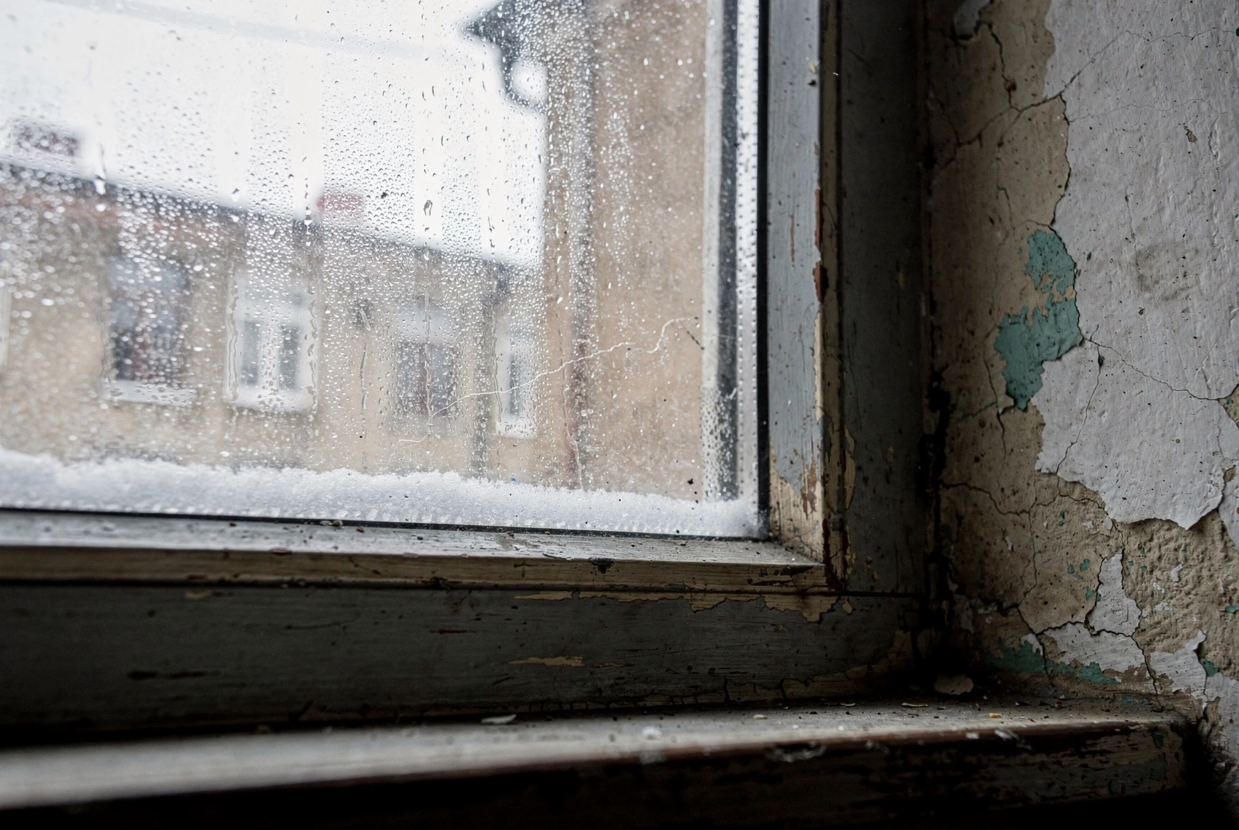 Close-up of condensation and moisture damage around an older apartment window